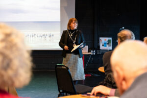 A woman giving a presentation in front of an audience of people