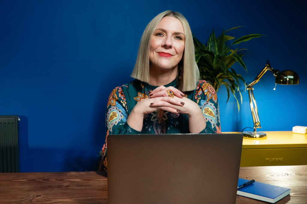 Ceri Hand sitting at a desk behind a laptop