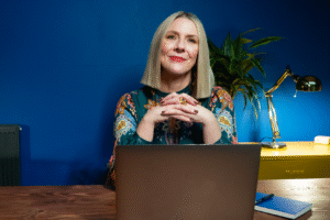 Ceri Hand sitting at a desk behind a laptop