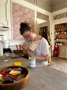 A young woman painting a pot at Ravn Clay pottery studio in Berwick